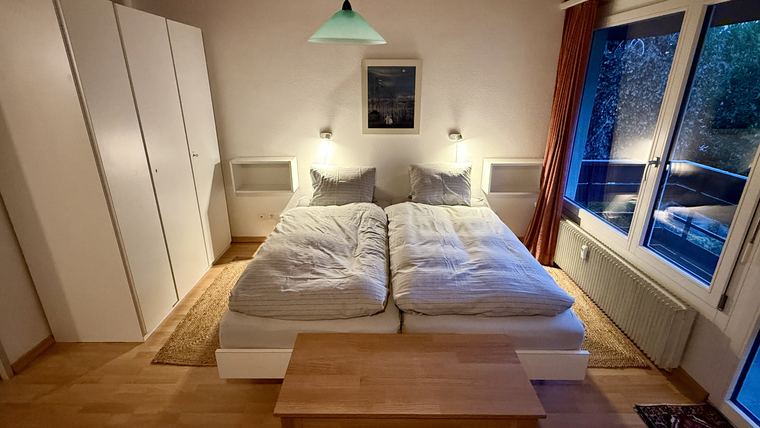 Schlafzimmer mit Doppelbett, Schrank und Fenster zum Balkon